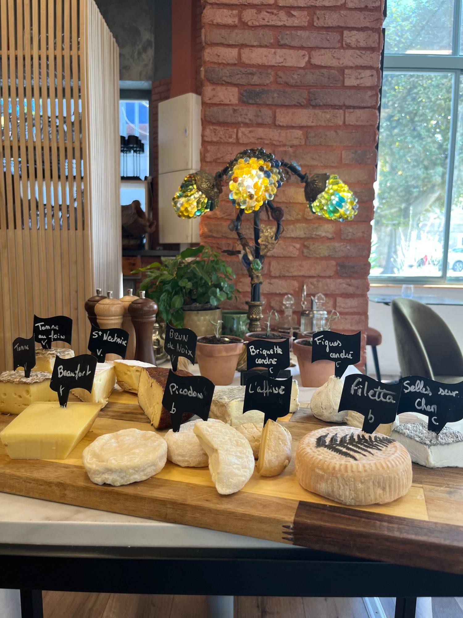 La salle des Poulettes : mur de briques, lampe ancienne et fromages affinés